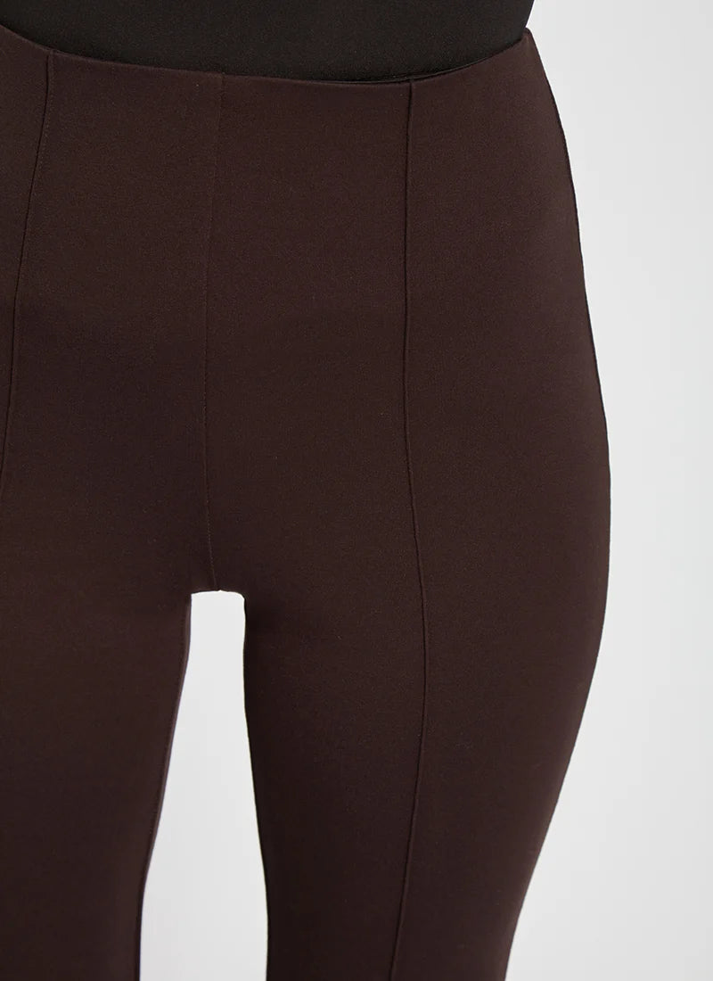 Close-up of a person wearing dark brown leggings against a light gray studio background.