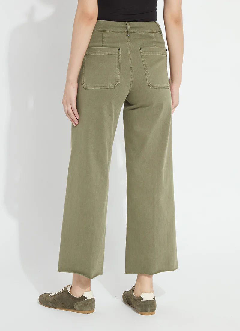 A model shown from the back wearing olive green wide-leg cropped pants, a black top, and olive green suede sneakers against a white studio background.