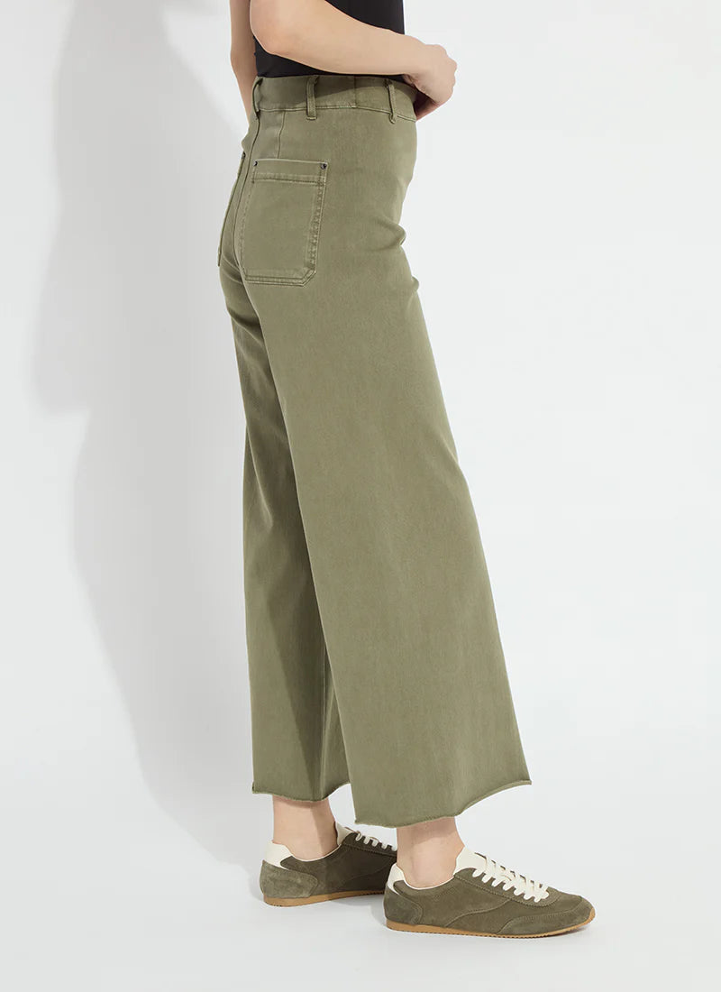 A person shown from the waist down wearing olive green wide-leg cropped pants and matching olive green sneakers against a plain white studio background.