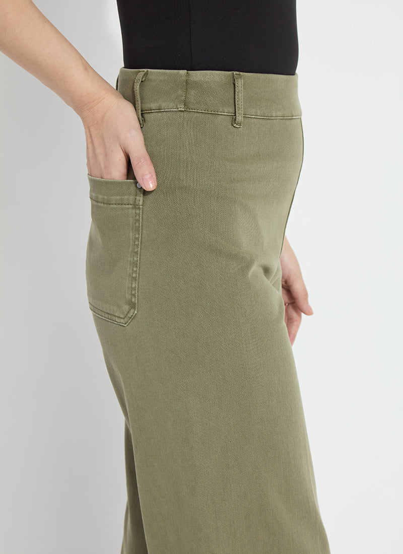 Close-up of a person wearing an olive green wide-leg skirt or long pants with a side pocket, paired with a black top against a light gray background.