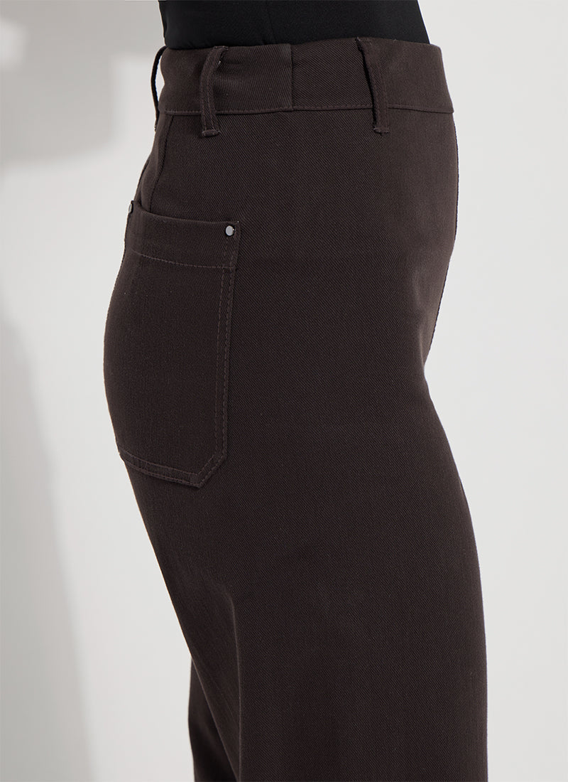 Close-up of a person wearing dark brown high-waisted pants, showing the side pocket, waistband, and fabric texture against a plain light background.