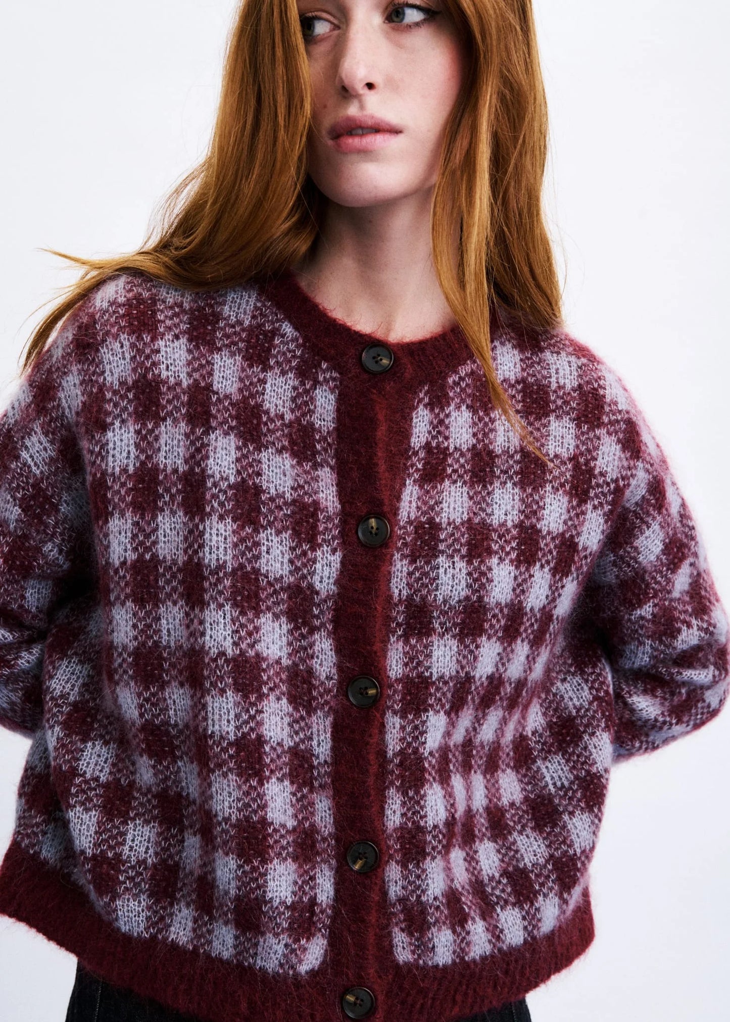 A woman wearing a fuzzy knit cardigan with a burgundy and light gray gingham check pattern, featuring dark buttons down the front.