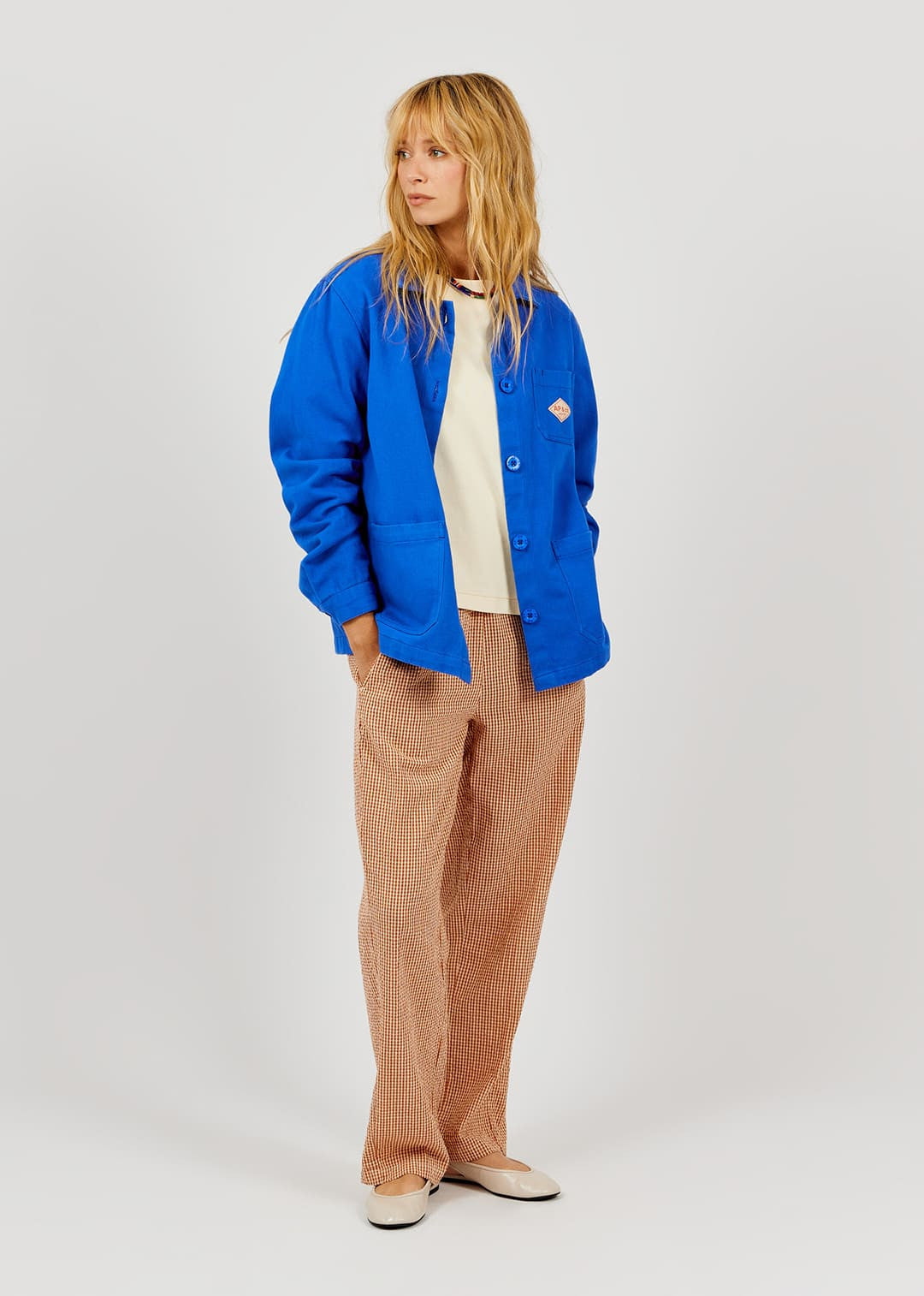 Person wearing a blue jacket and brown pants on a white background