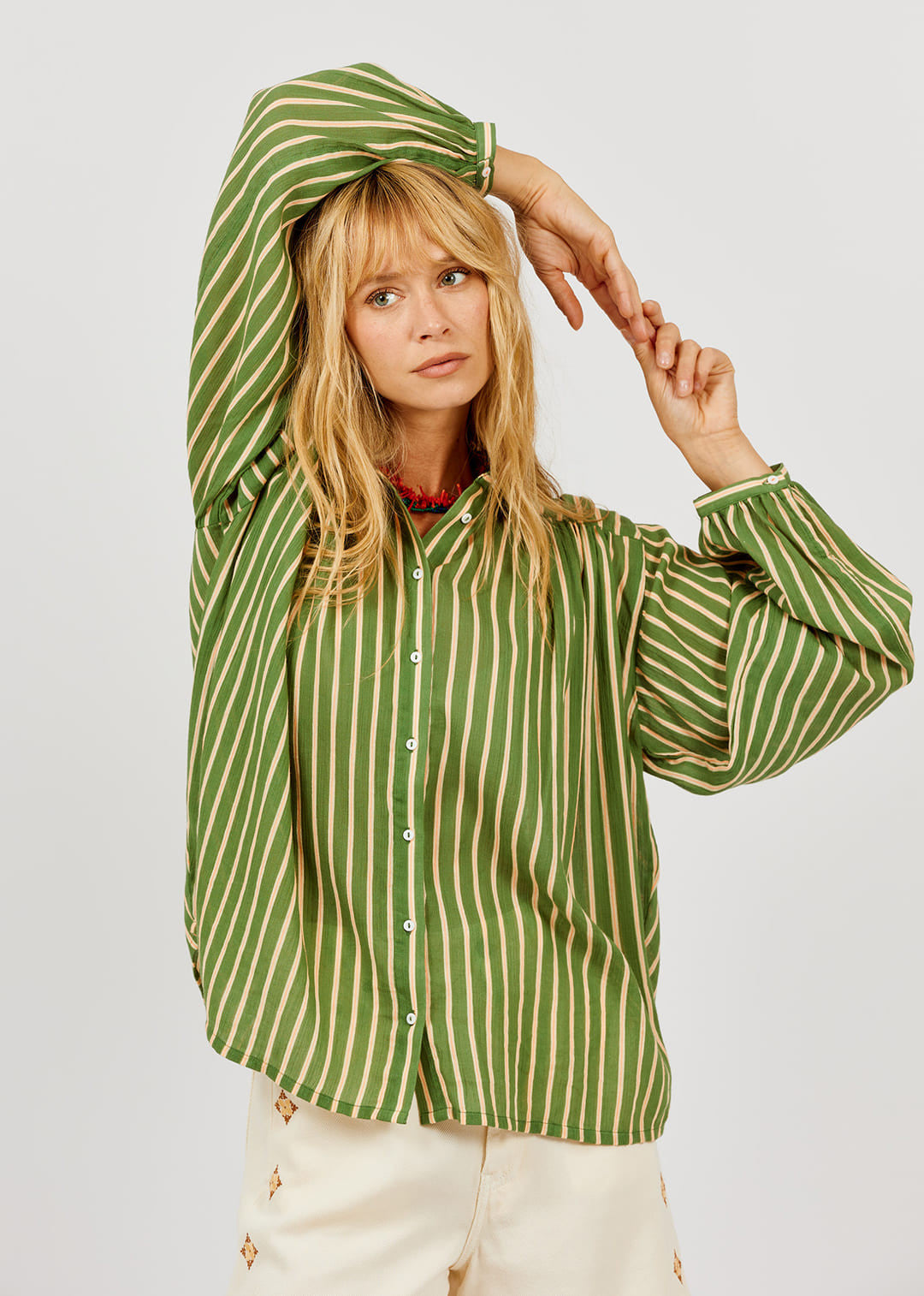 Woman wearing a green and beige striped shirt against a plain background