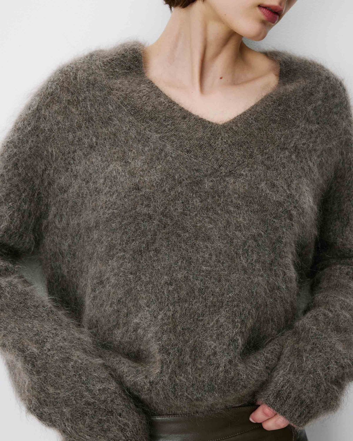 Person wearing a fluffy gray sweater against a plain background