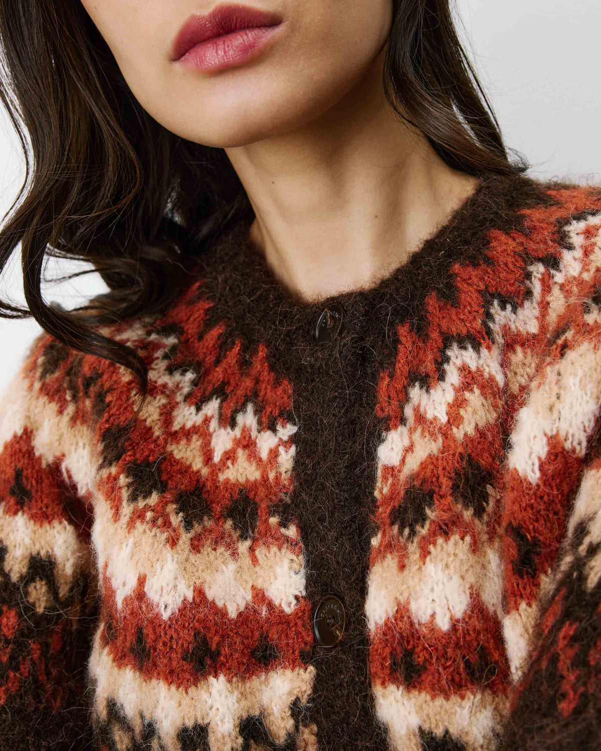Close-up of a person wearing a patterned sweater with red, white, and brown colors.
