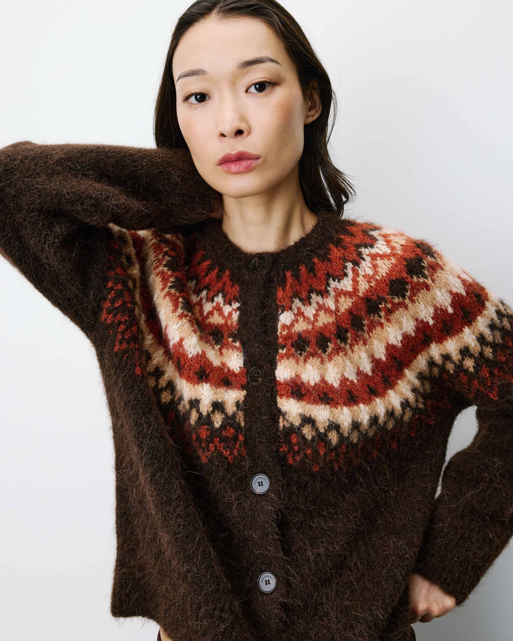 Woman wearing a brown sweater with a patterned yoke against a white background