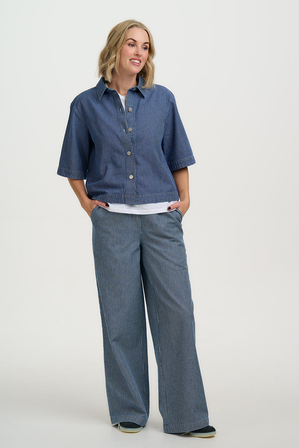 Woman wearing a blue denim shirt and pants on a white background