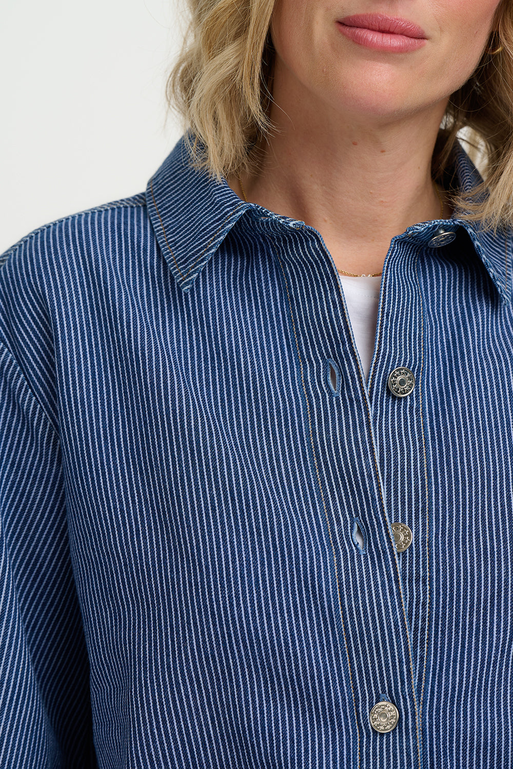 Close-up of a person wearing a blue striped shirt with a neutral background