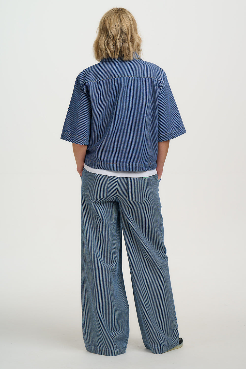 Person wearing a blue outfit with wide-leg pants on a white background