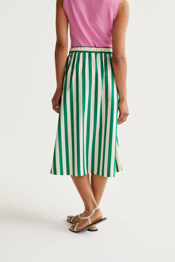 Person wearing a green and white striped skirt on a plain background