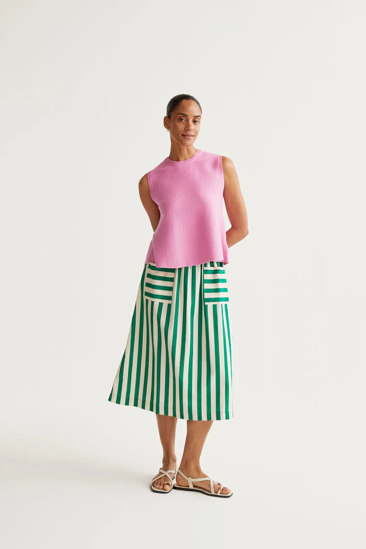 Woman wearing a pink sleeveless top and green and white striped skirt on a white background