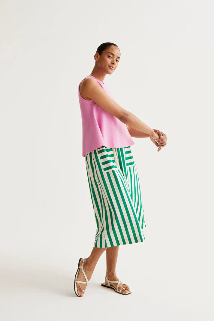 Woman wearing a pink sleeveless top and green and white striped skirt on a white background