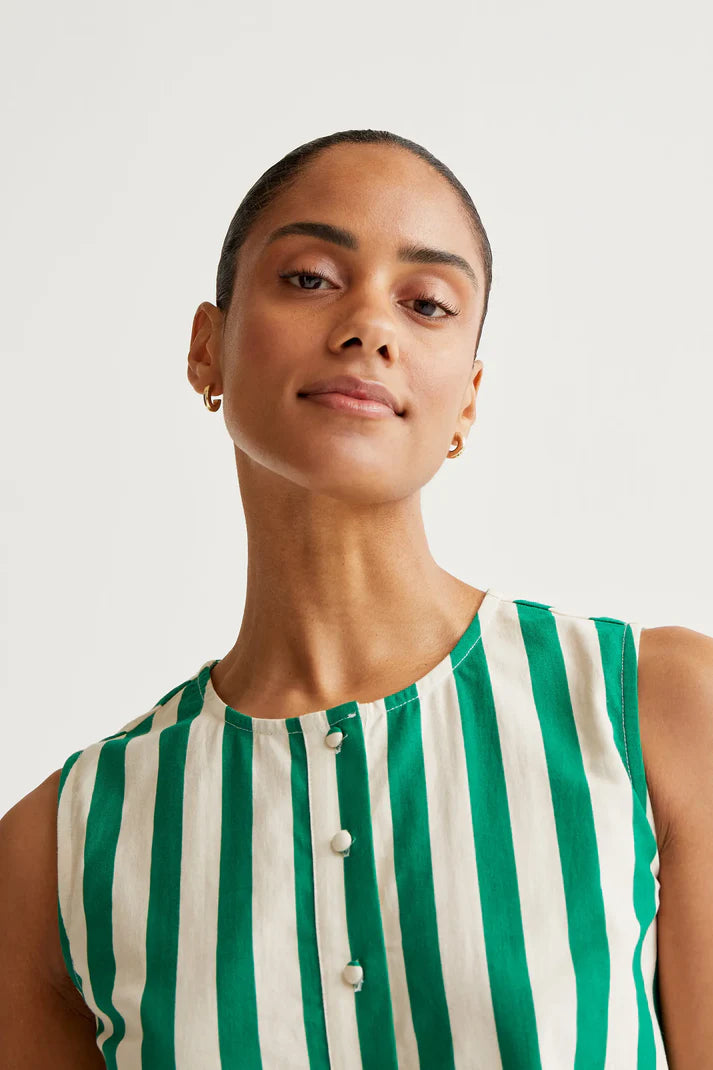 Woman wearing a green and white striped sleeveless top against a plain background