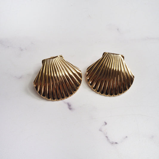 Gold shell-shaped earrings on a marble surface