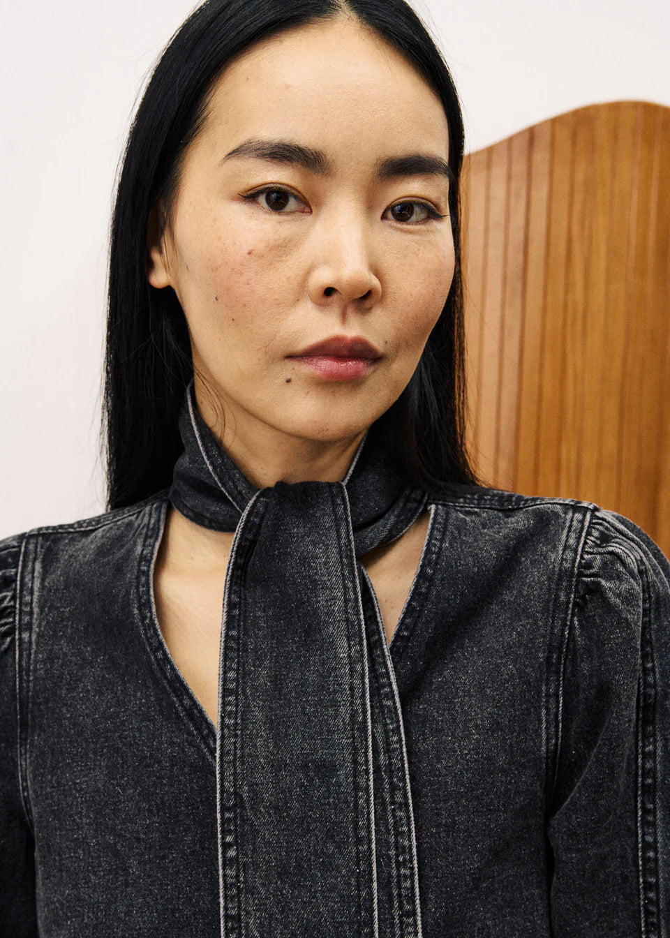 Woman wearing a dark denim jacket with a plain background