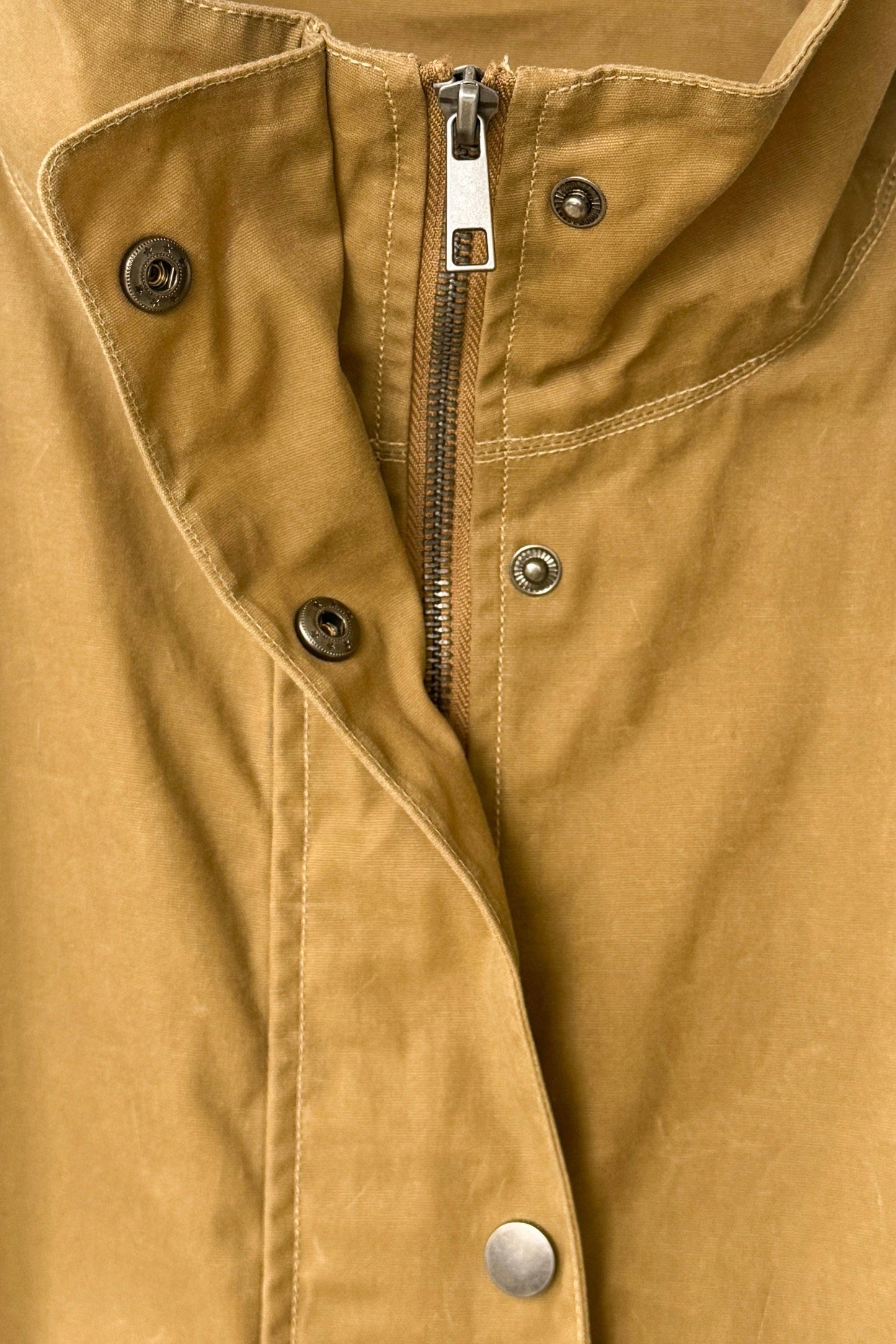 Close-up of a brown jacket with buttons and a zipper
