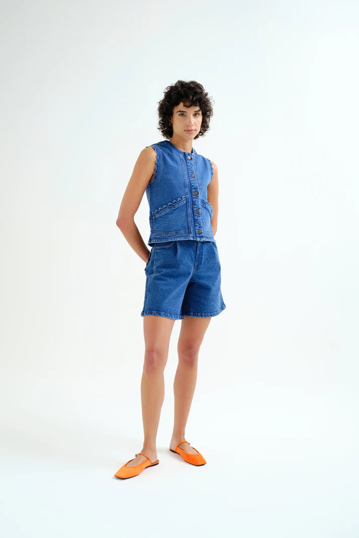 woman wearing blue denim vest and blue shorts on white background