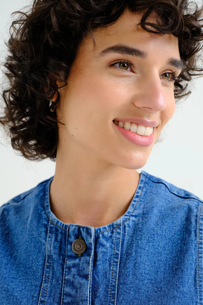Person wearing a blue denim shirt against a white background
