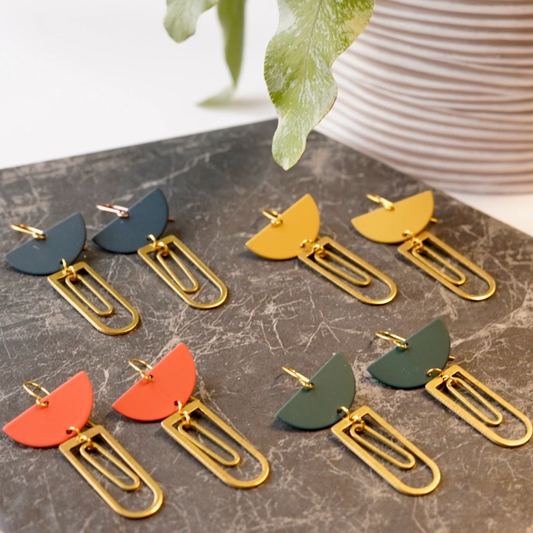 Set of colorful earrings on a marble surface with a plant in the background