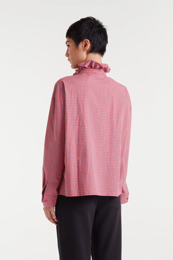 Person wearing a red and white checkered blouse with ruffled collar on a white background