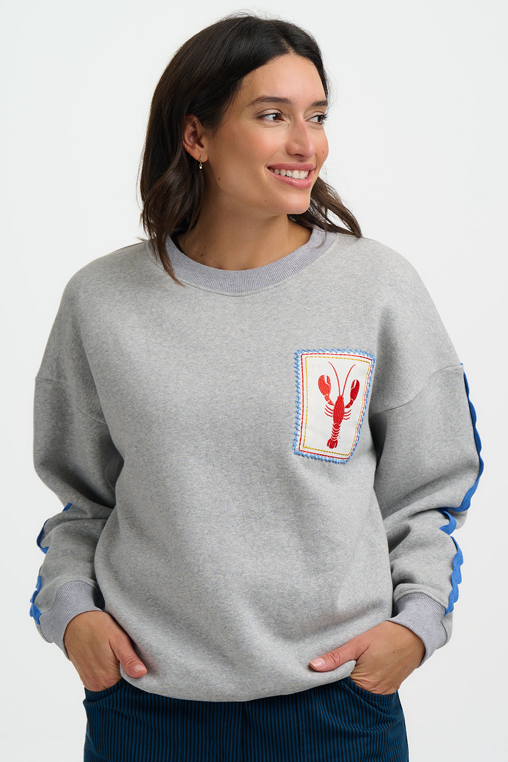 Woman wearing a gray sweatshirt with a lobster graphic on a white background