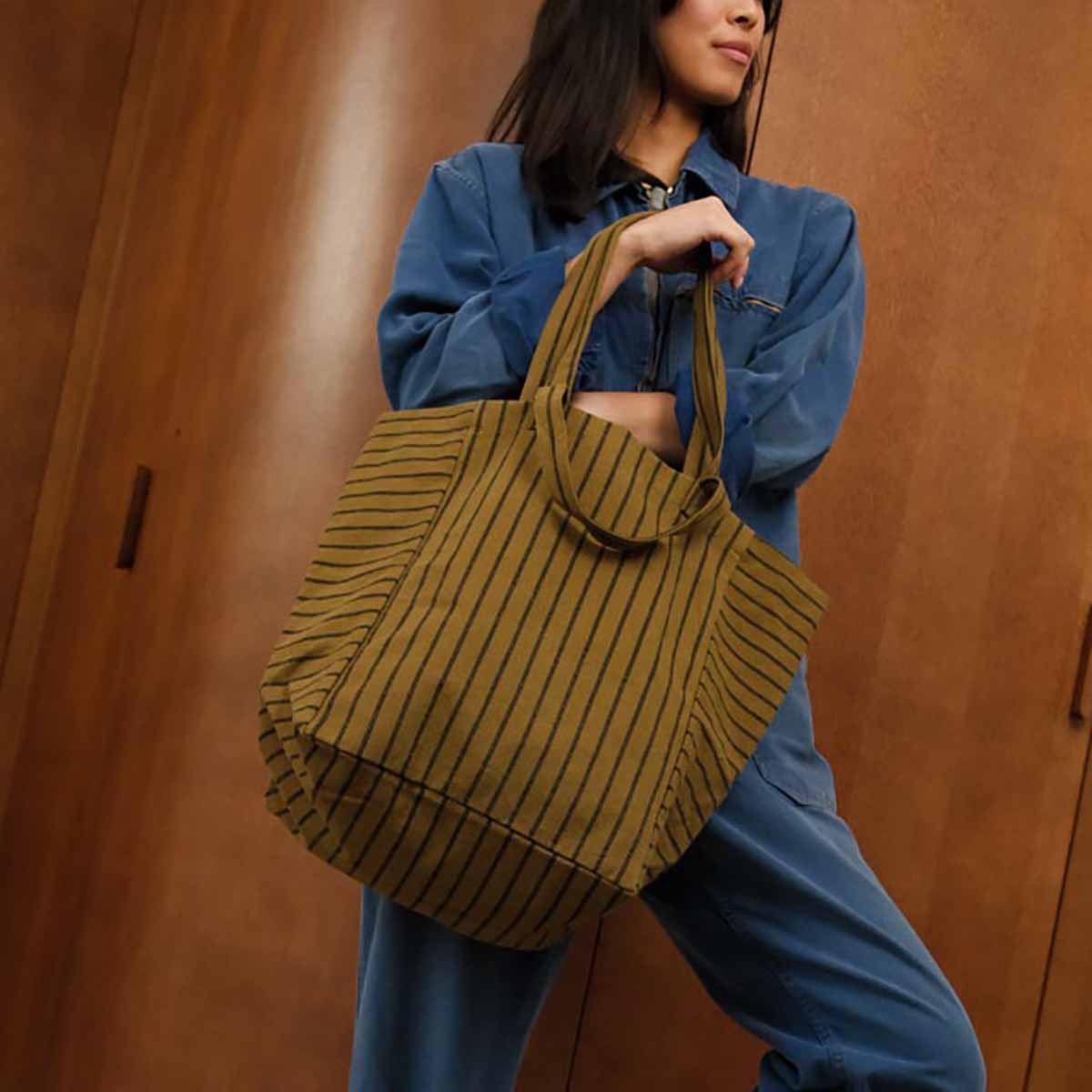 Person holding a striped bag against a wooden background