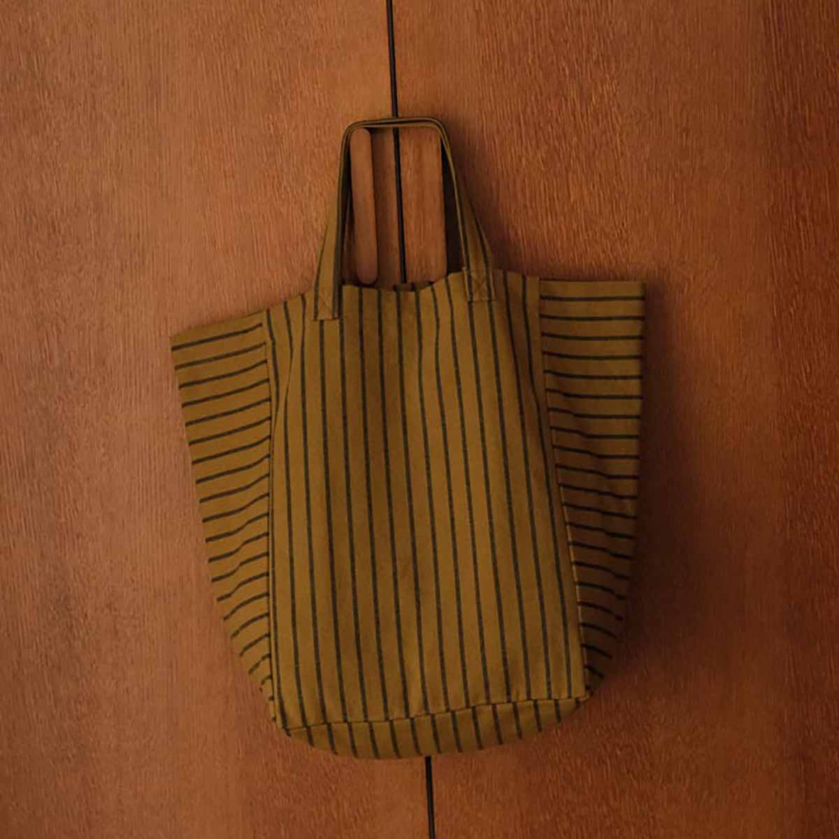 Striped tote bag hanging on a wooden surface