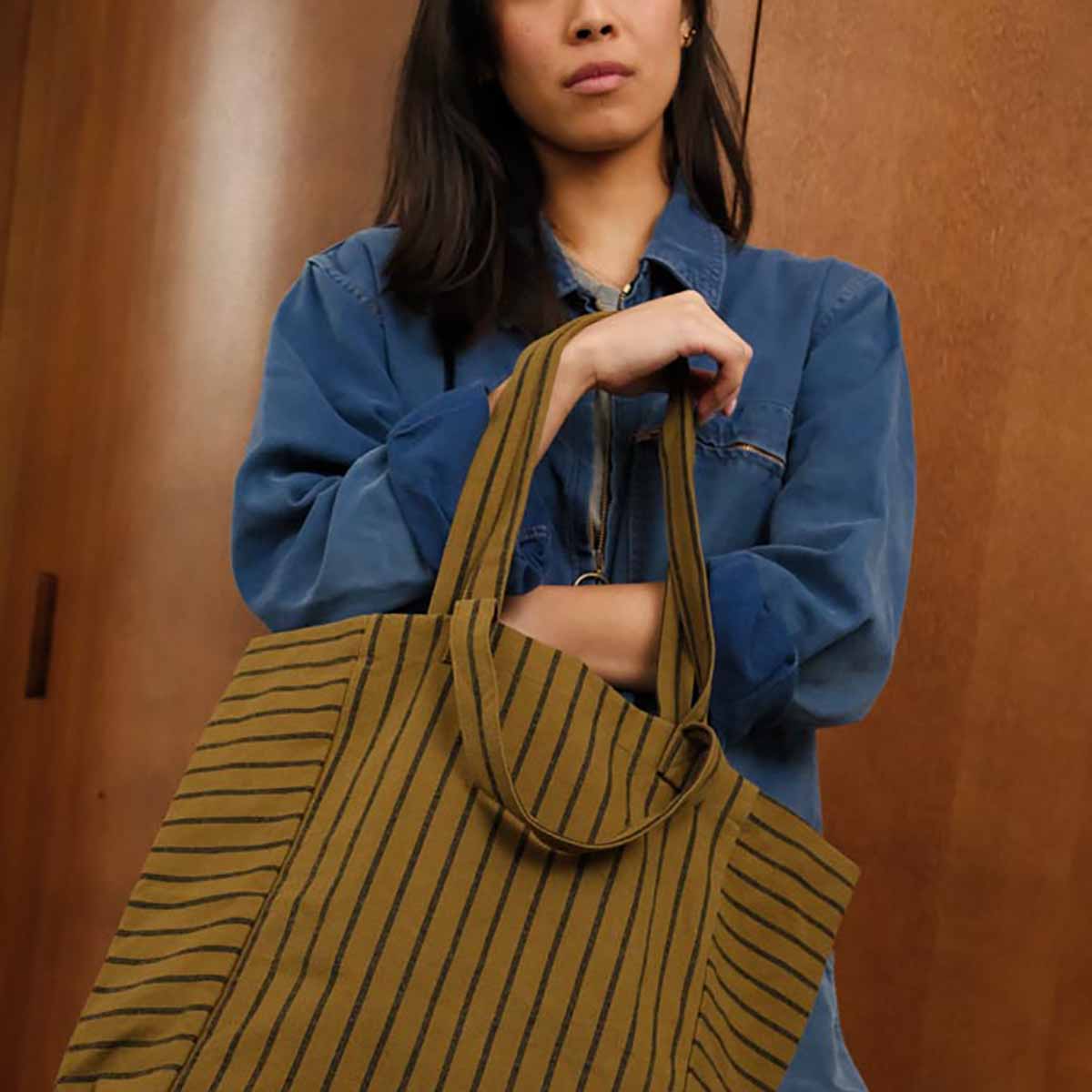 Person holding a striped brown bag against a wooden background