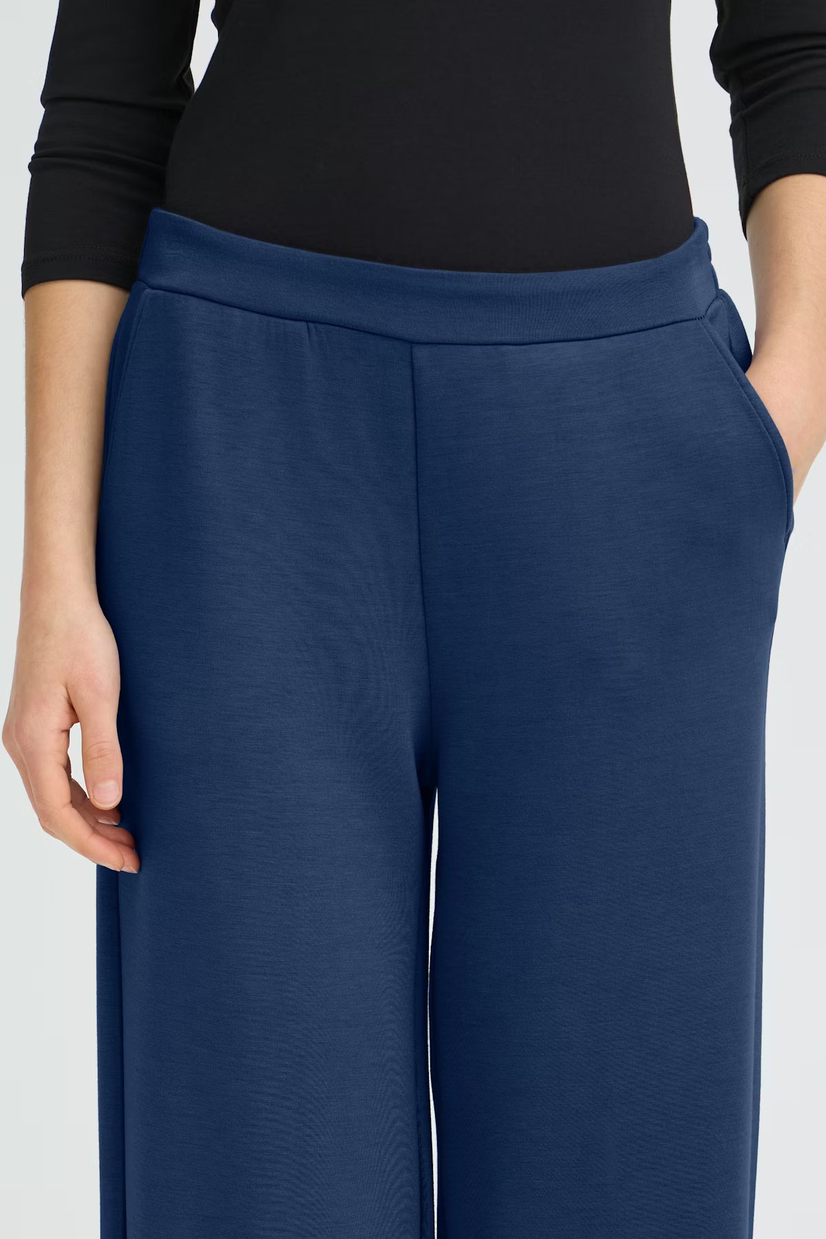 Navy blue pants worn by a person on a light gray background