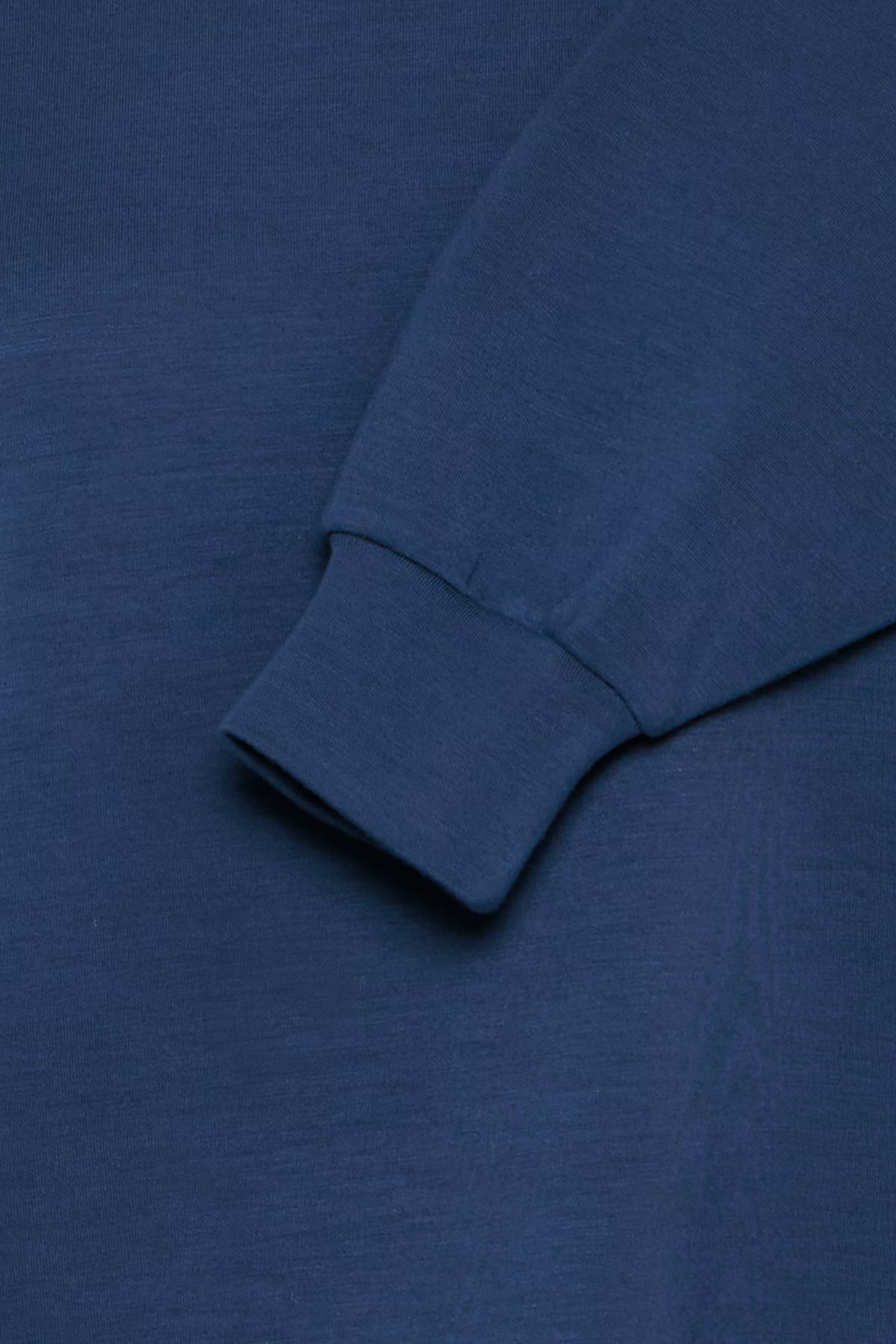 Close-up of a blue long-sleeve shirt with a rolled-up sleeve.