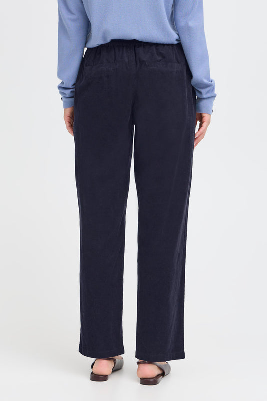 Person wearing navy pants and a light blue shirt on a white background