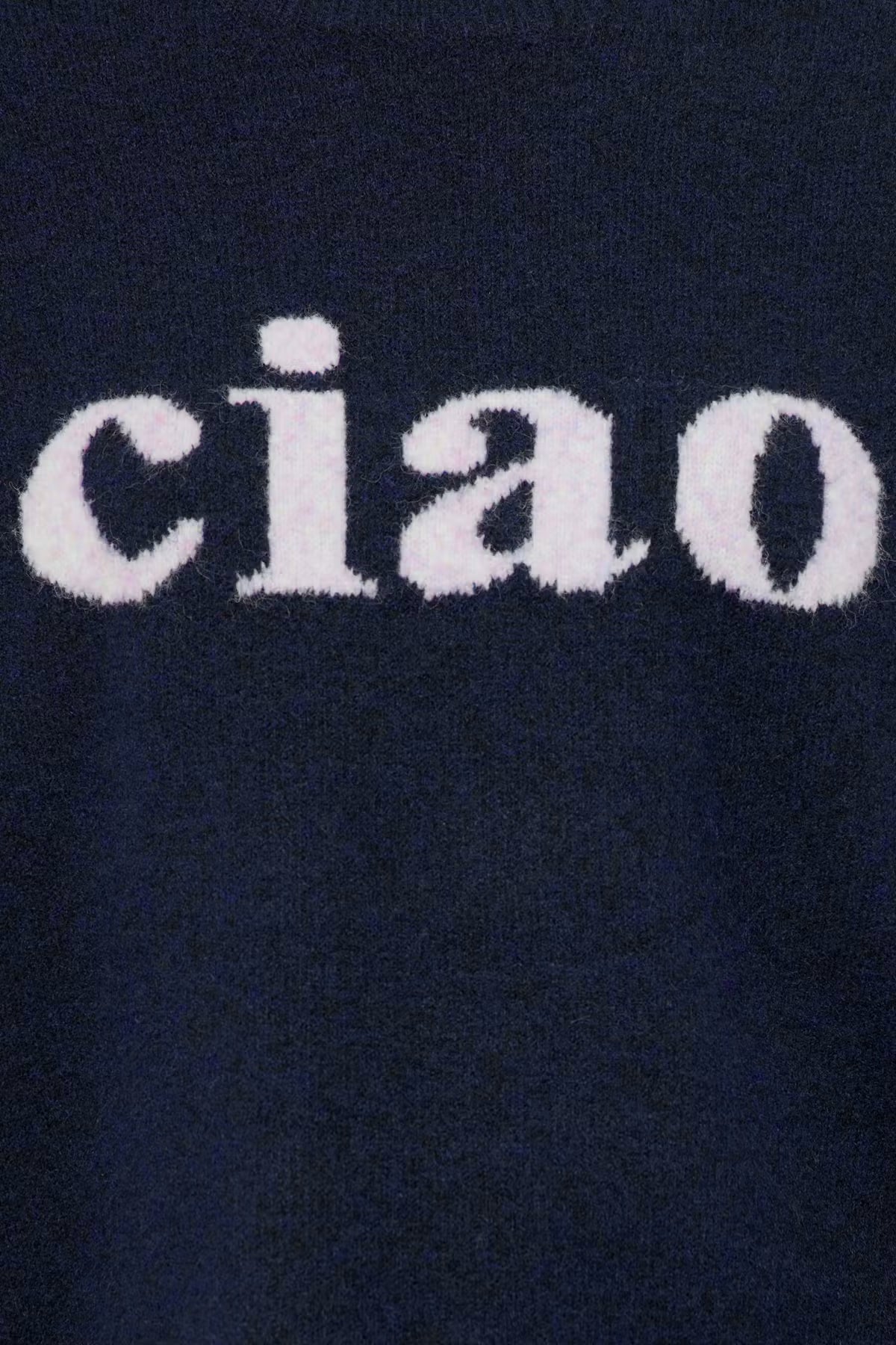Close-up of a dark navy knit fabric with the word 'ciao' in white fuzzy lettering across the top.