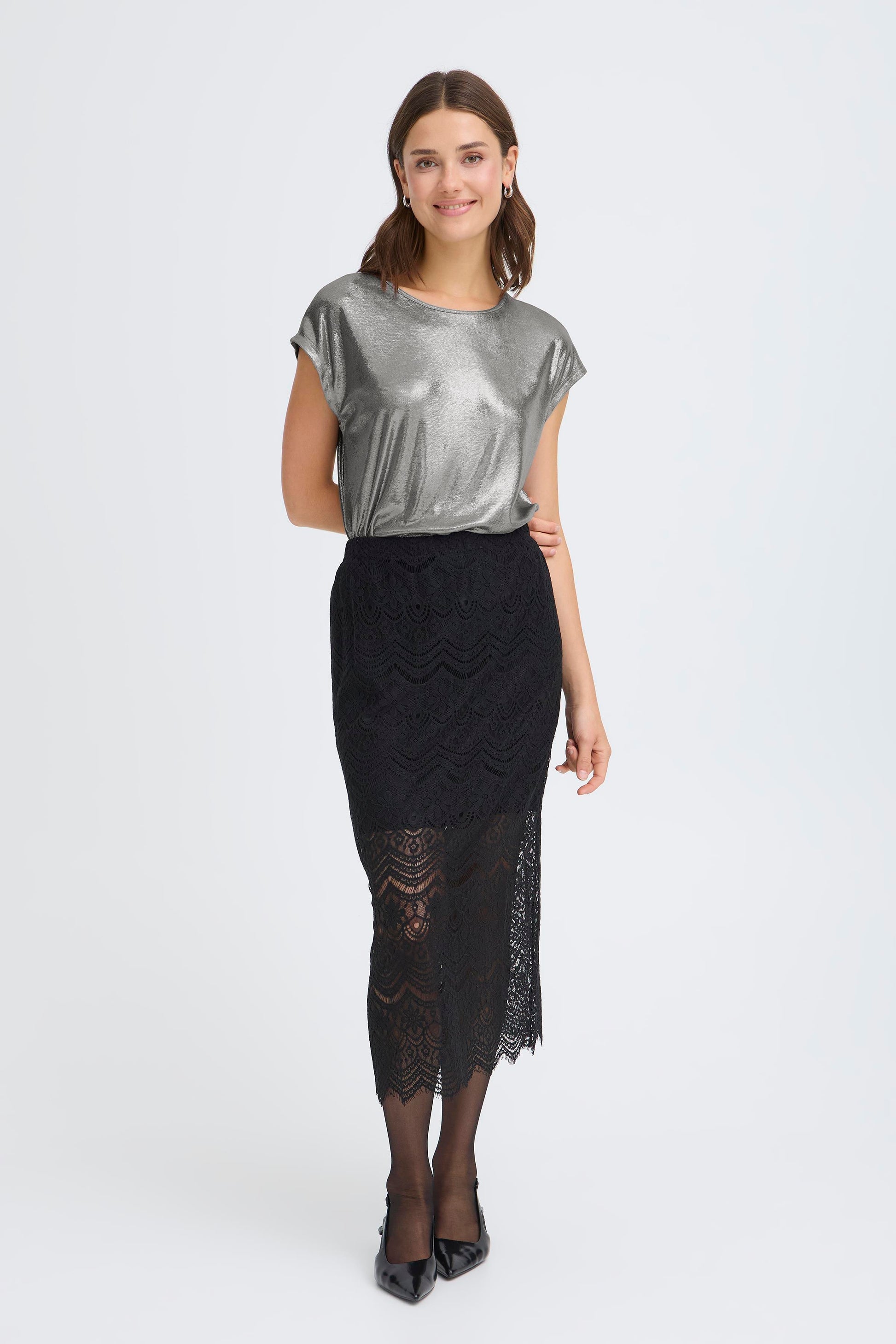 Woman wearing a silver top and black lace skirt on a white background