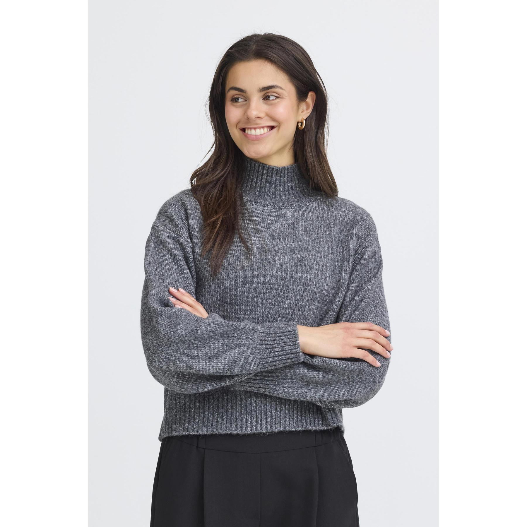 Woman wearing a gray sweater with arms crossed on a white background