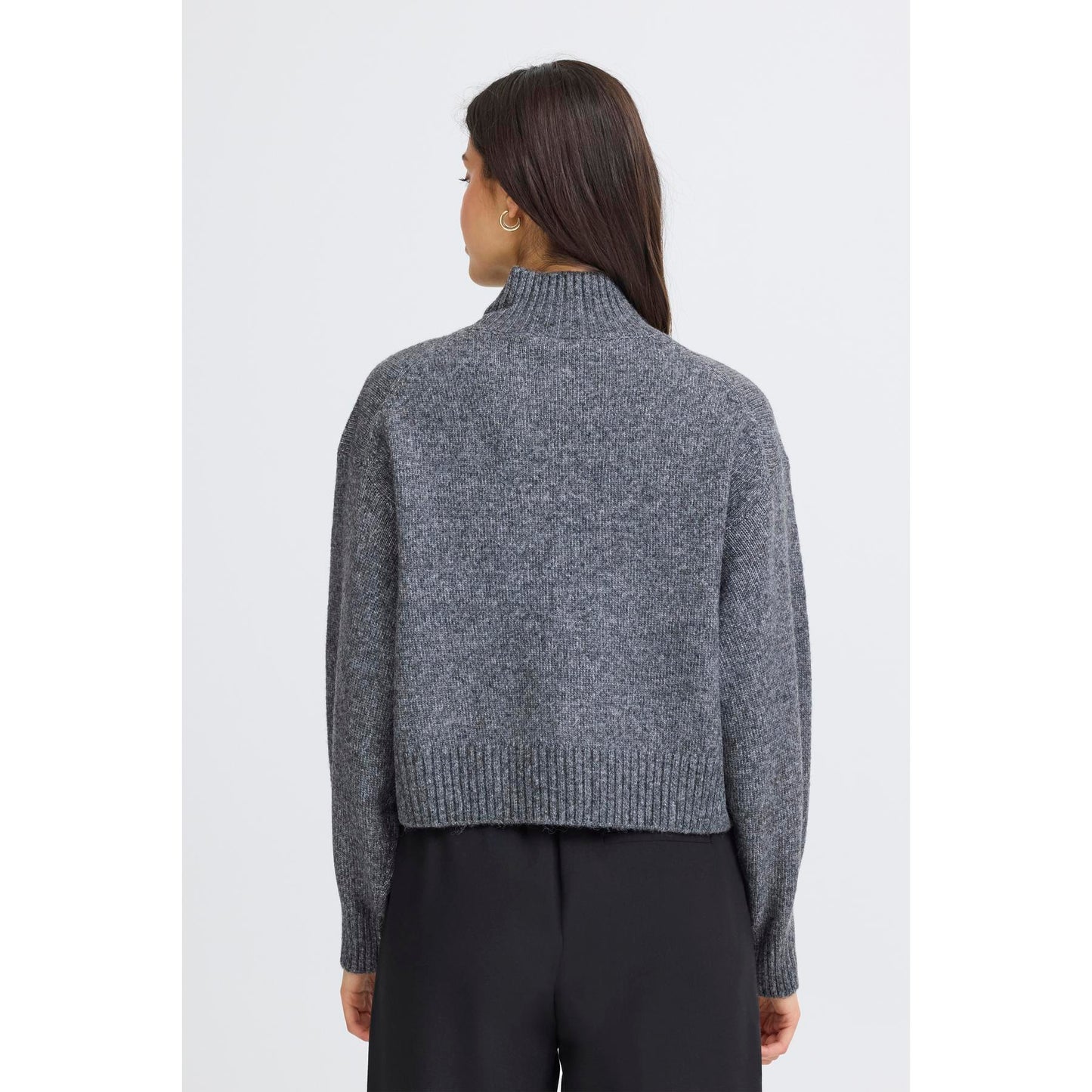 Person wearing a gray knit sweater on a white background
