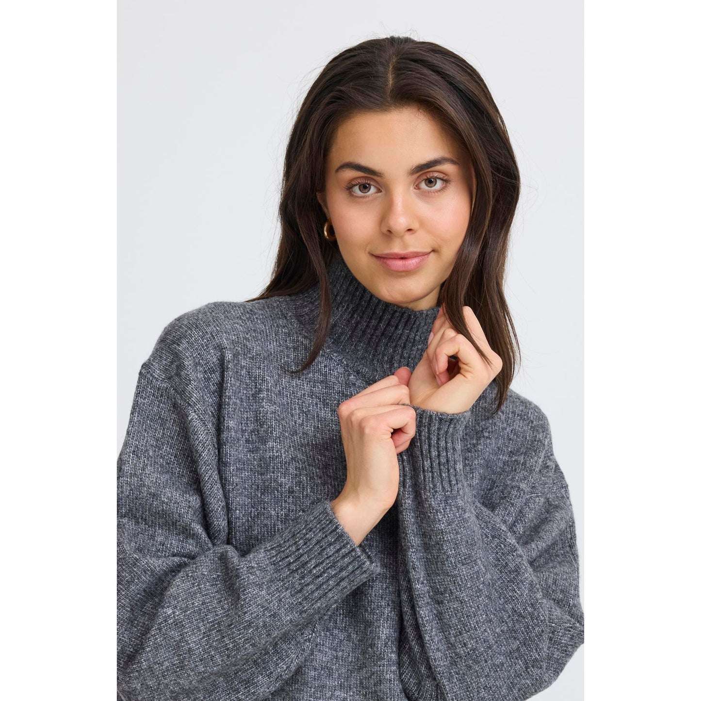 Woman wearing a gray sweater against a white background