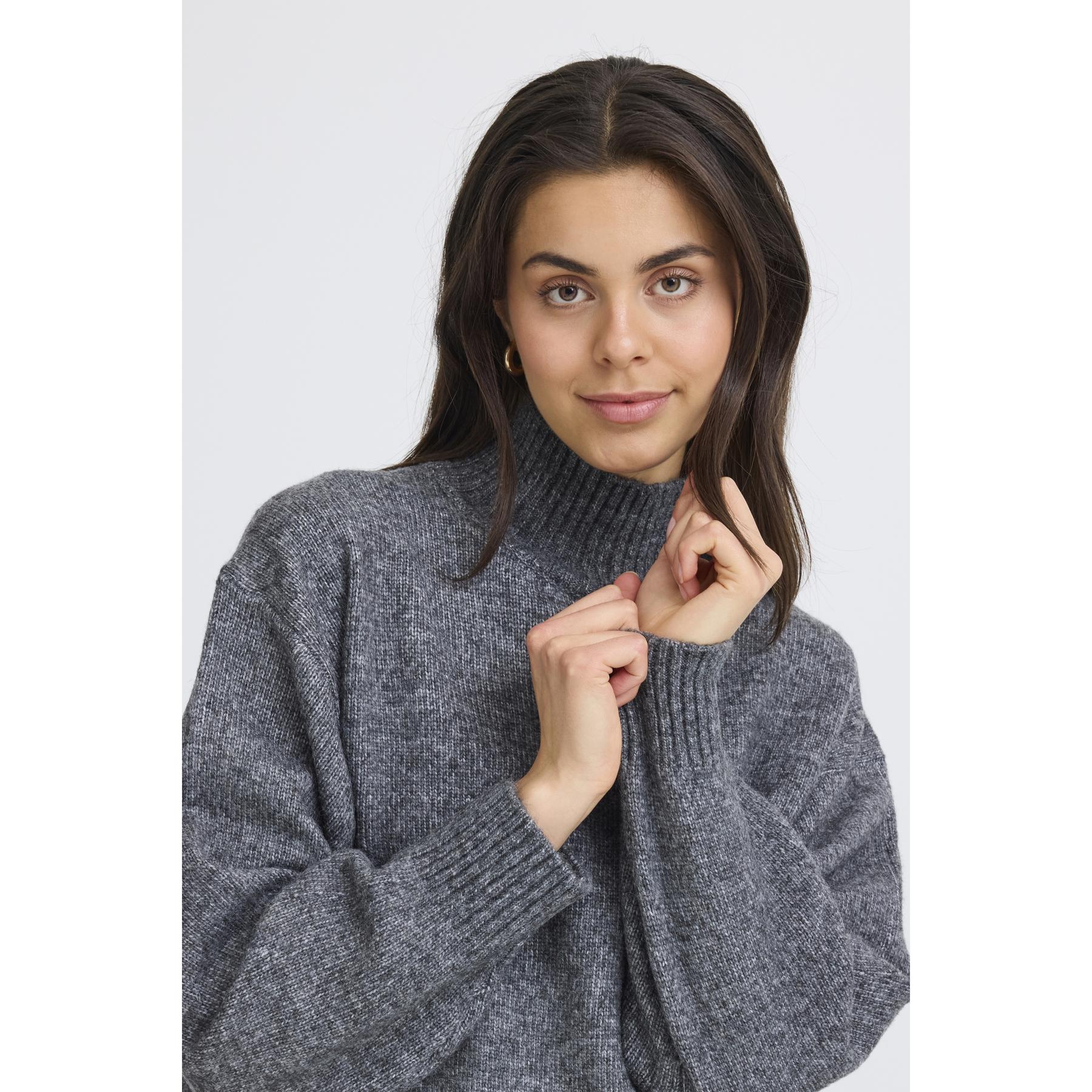 Woman wearing a gray sweater against a white background