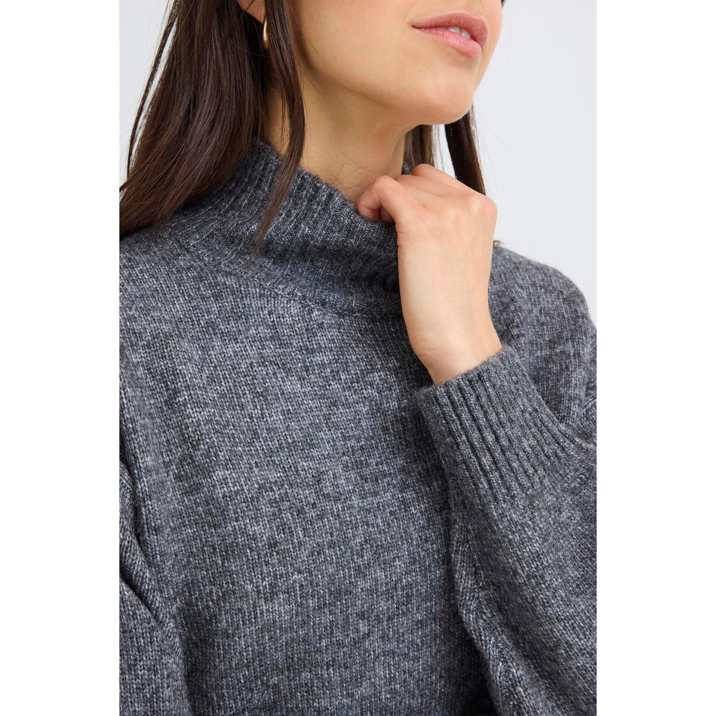 Close-up of a person wearing a gray sweater with a plain background