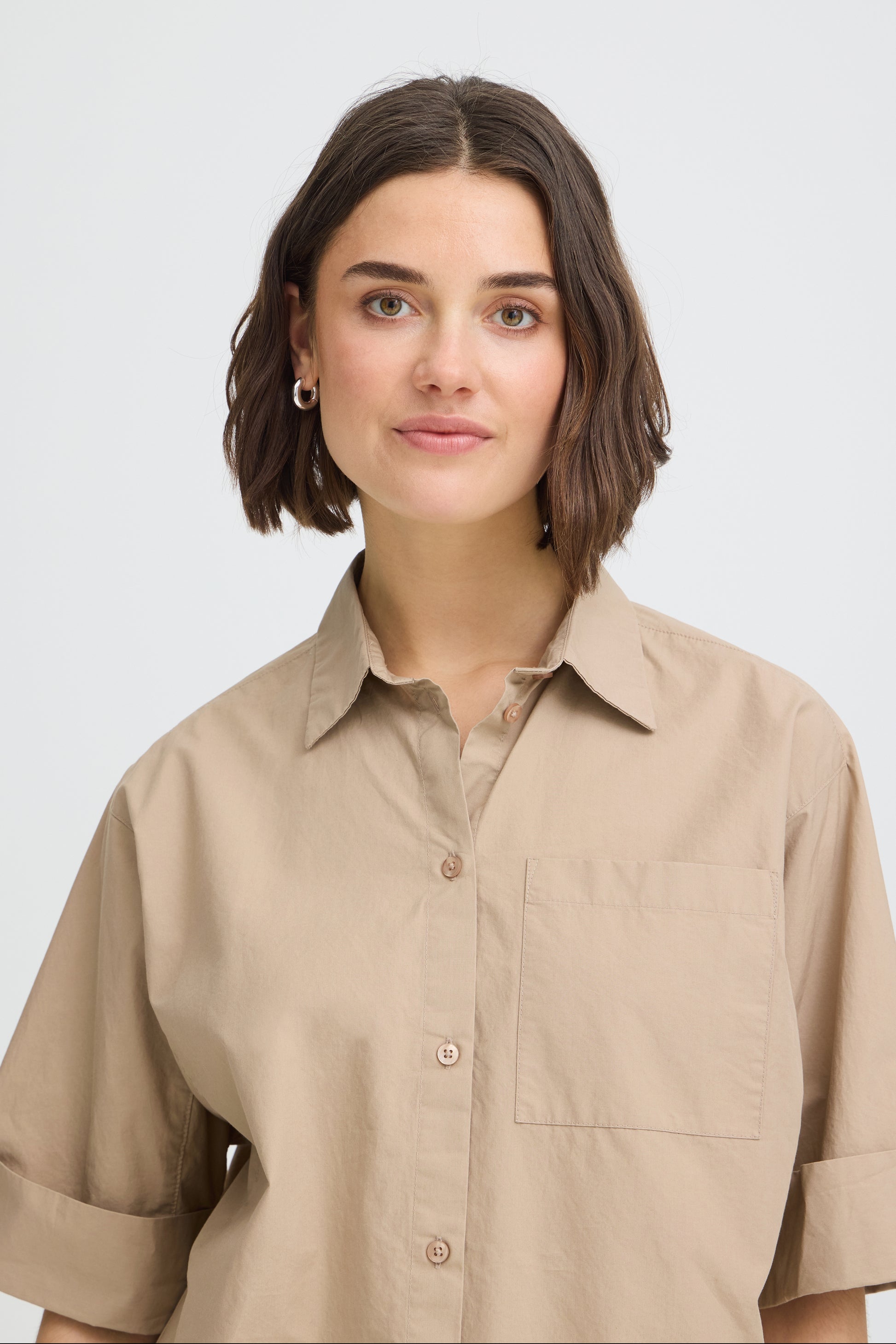 Woman wearing a beige shirt against a plain background