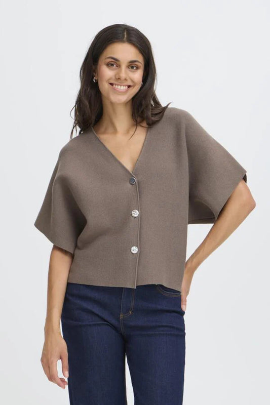 Woman wearing a brown cardigan over a blue top on a white background