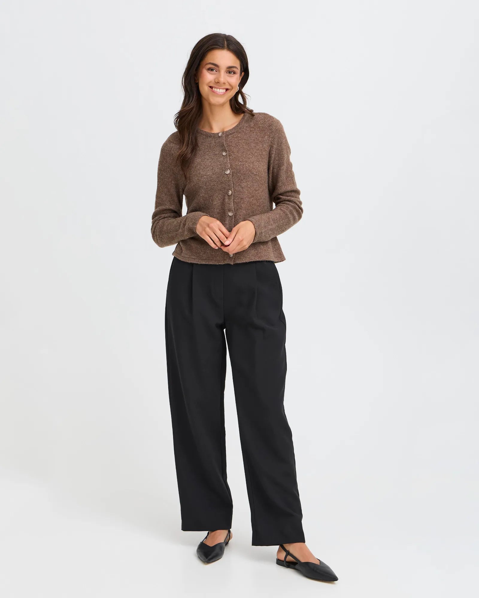 Woman wearing a brown cardigan and black pants on a white background