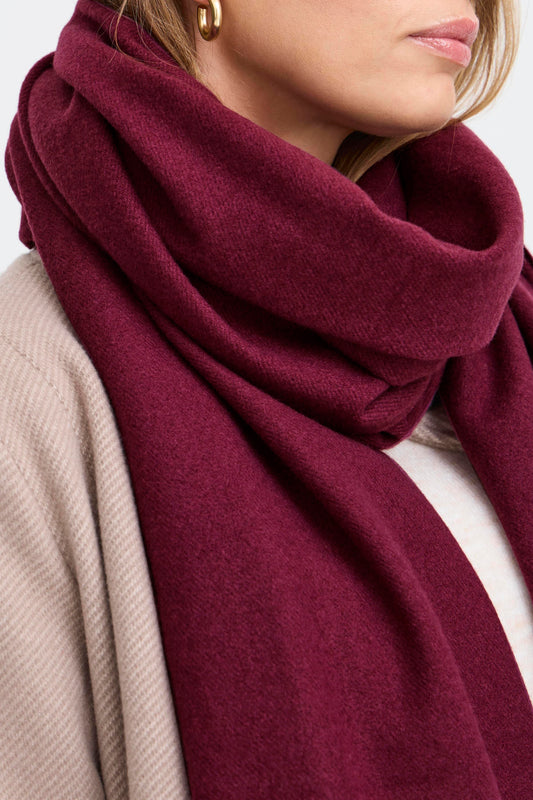 Close-up of a person wearing a burgundy scarf with a neutral background