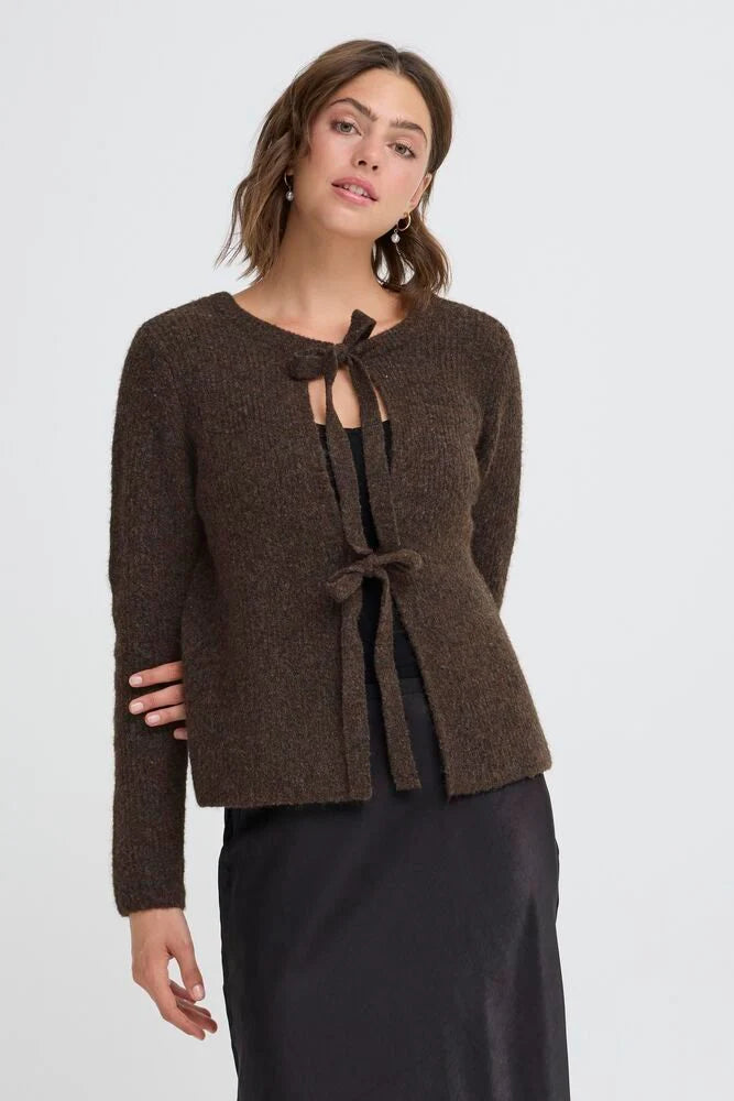 Woman wearing a brown knitted cardigan with a tie detail on a white background