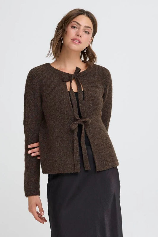 Woman wearing a brown knitted cardigan with a tie detail on a white background