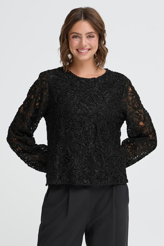Woman wearing a black lace top against a white background