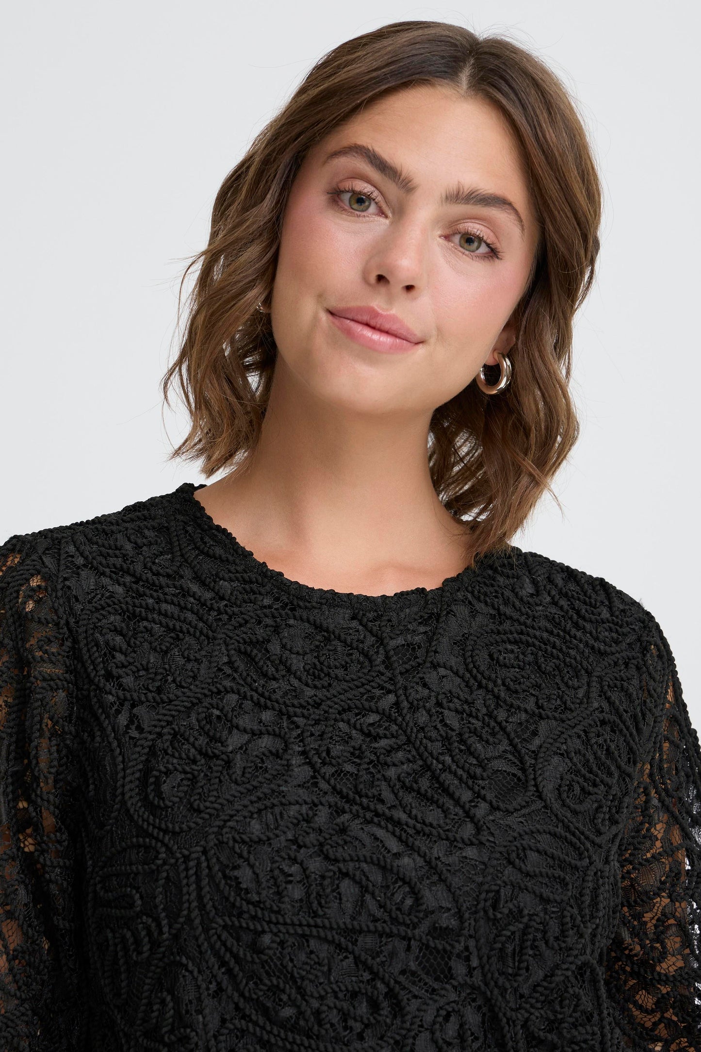 Woman wearing a black lace dress against a white background