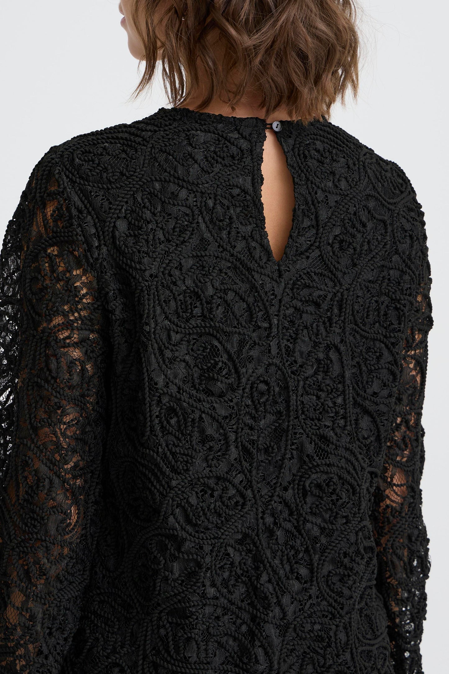 Black lace dress with a cut-out back on a white background