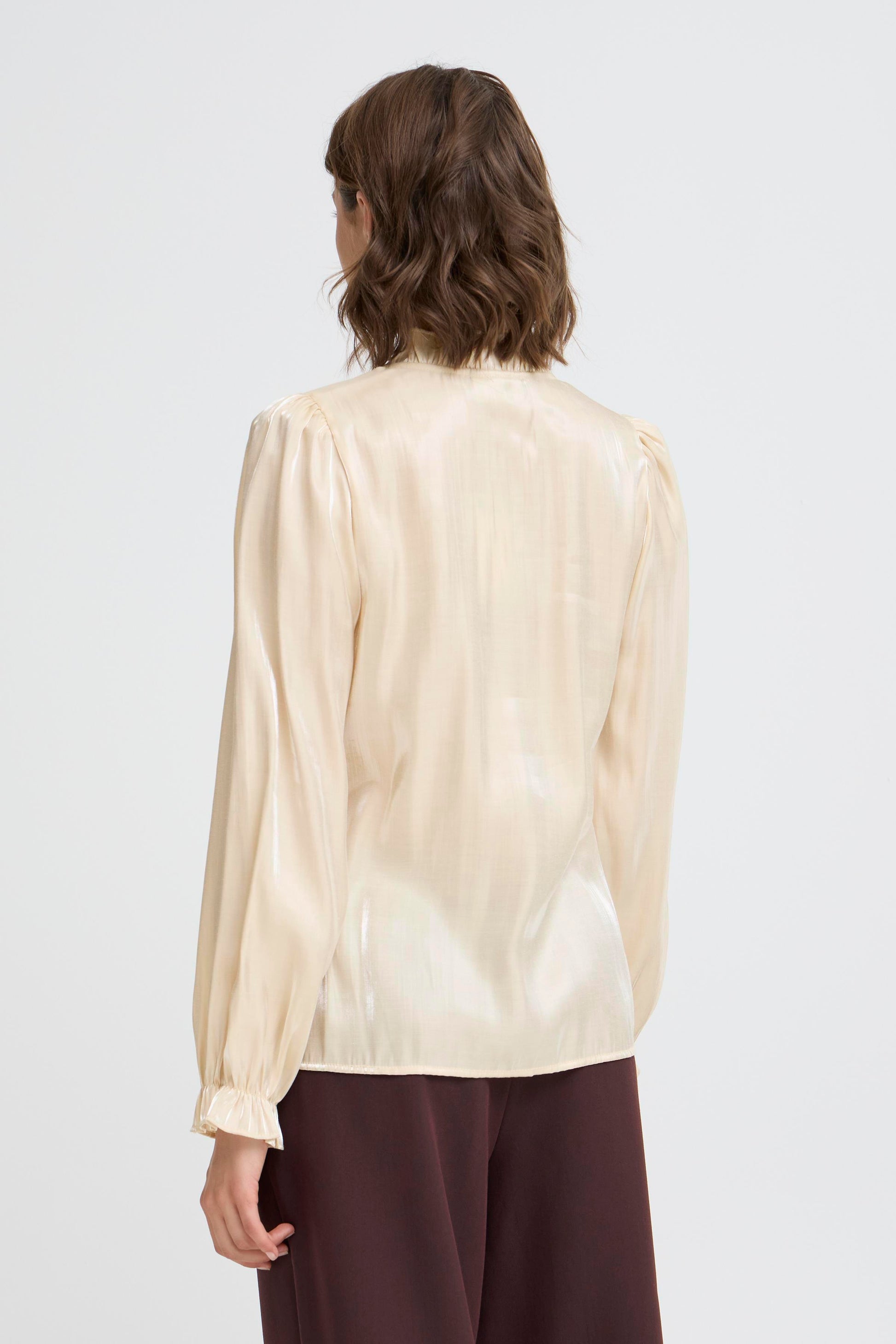 Woman wearing a beige blouse with long sleeves on a white background