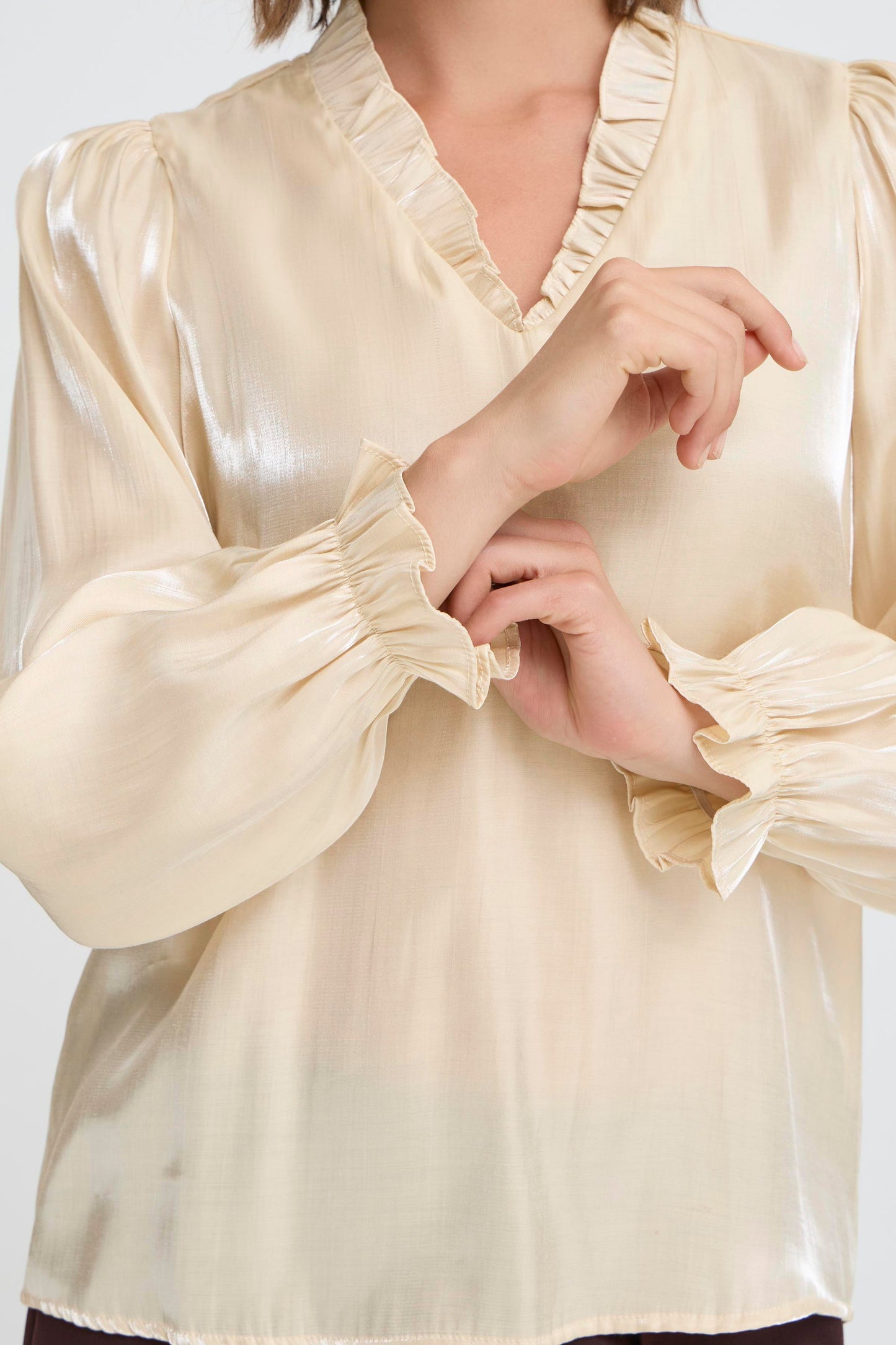 Beige blouse with ruffled sleeves on a plain background